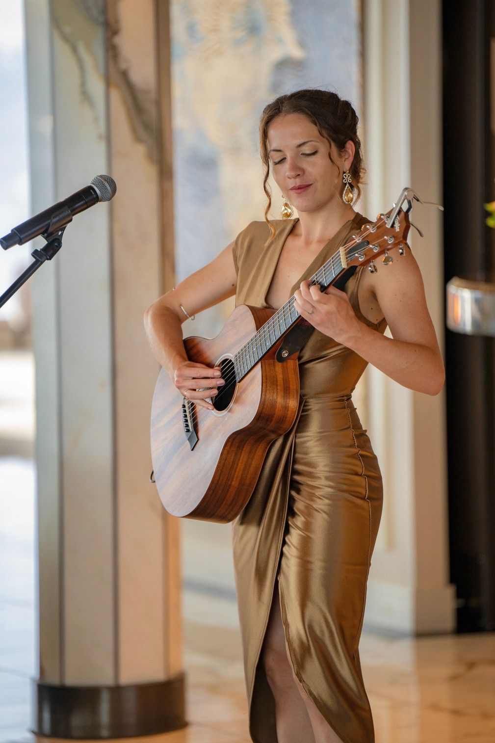 Lisette Luján cantando y tocando la guitarra con vestido dorado